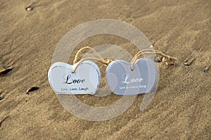 Two inscribed wooden love hearts in the quick sand