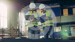 Two inspectors are having a discussion in a factory unit professional heavy industry engineers.