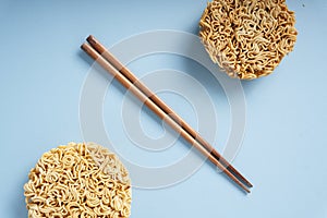 Two instant noodles and chopstick over blue background