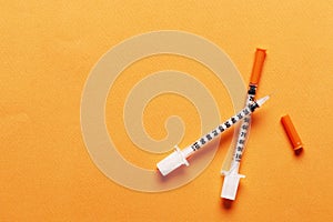 Two insulin syringes on a colored background with place