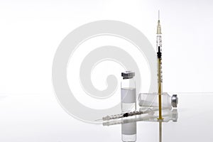 Two insulin syringes and glass tubes of medicaments on the glass table.Empty space