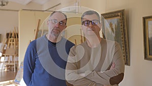 Two intelligent men in an art gallery look at a picture and talk about art