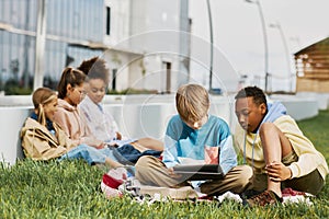 Two intercultural schoolboys looking at tablet screen