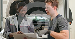 two international mechanics using modern technolodies when repair broken cars