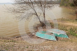 Two inverted green rowing boats on the lake shore