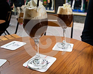 Two Irish coffees with whipped cream, dark coffee and alcoholic whisky sat on a table in a cafÃ© in Europe. European cafÃ© culture