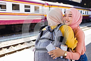 Two Islamic women hugged on a train platform. Friendship on the go. Family reunion concept