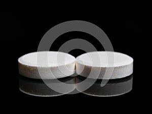 Two isolated pills or medicine tablets on black background