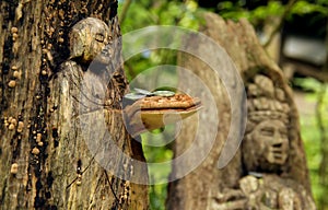 Two Japanese wood carvings of a Buddha in a forest with a mushroom and coins