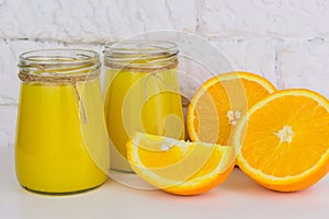 Two jars of fresh orange juice on a white background. Close-up.