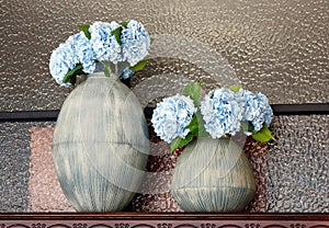 Two jars of hydrangeas placed on the decorative cabinet.