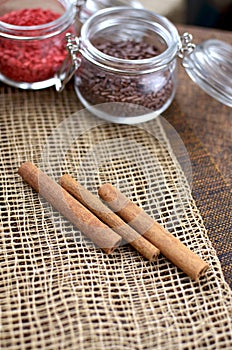 Two jars with sugar confectionery additives and cinnamon sticks