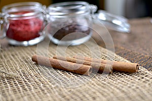 Two jars with sugar confectionery additives and cinnamon sticks