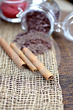 Two jars with sugar confectionery additives and cinnamon sticks