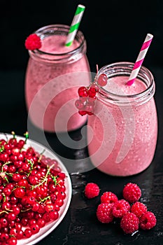 Two jars with yogurt smoothie with cranberry, raspberry on black background. Selective focus