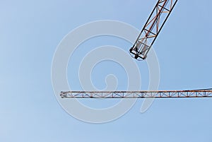 two jib cranes against a cloudless blue sky.