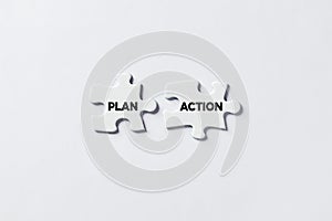 Two Jigsaw puzzle pieces is connecting with the words plan and action. To take action and to realize the plans