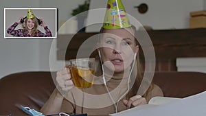 Two joyful Caucasian women in party hats celebrating in video chat. Positive smiling girls laughing and chatting online