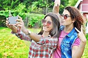 Two joyful fanny pretty girls having fun taking a selfie on mobile