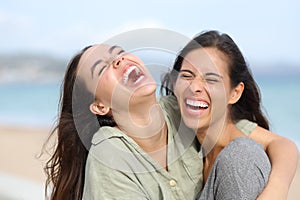 Two joyful friends laughing hilariously on the beach