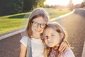 Two joyful girls hugging against the sunset.