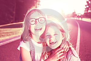 Two joyful girls hugging and smiling against the sunset.