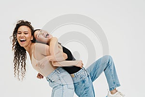 Two joyful girls leaning at backs of each other having fun isolated