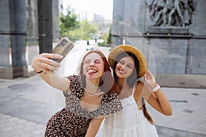 Two joyful girls taking a selfie on the city street