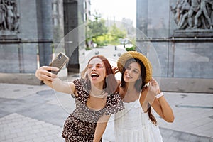 Two joyful girls taking a selfie on the city street