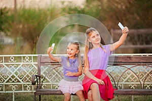 Two joyful girls taking selfie at park.