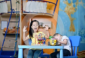 Two joyful kids boy and girl play enthusiastically at the table with toys