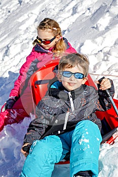 Two joyful kids playing on the snowing mountain on a winter day.