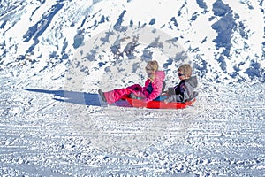 Two joyful kids sledding down the hills on a winter day.