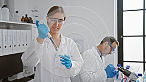 Two joyful lab mates, woman and man, pouring liquid into a sample pipette together, navigating the path of medical science, gloves