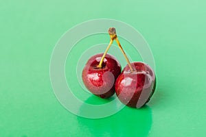 Two juicy berries of a red cherry on a green background
