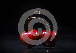 Two juicy cherries on a black background