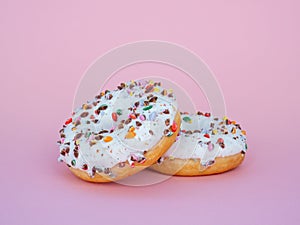 Two juicy fresh sweet donuts with sugar icing and sprinkles on a pink background. Round donut with a hole. Funny mood