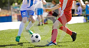 Two junior level soccer players running and kicking a soccer ball