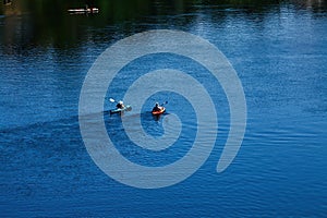 Two Kayaks Moving Down River Away From Camera