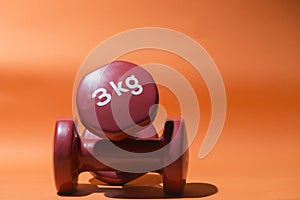 Two 3 kg weights on orange background