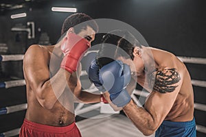 Two kickboxers fighting on a boxing ring and looking aggressive