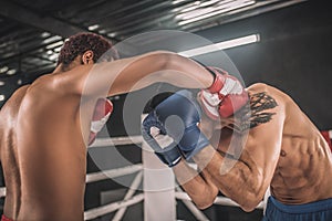 Two kickboxers fighting on a boxing ring and looking aggressive