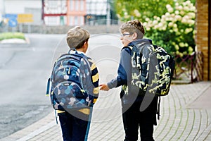 Two kid boys with backpack or satchel. Schoolkids on the way to school. Healthy smiling children, brothers and best