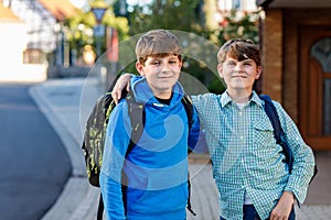 Two kid boys with backpack or satchel. Schoolkids on the way to school. Healthy smiling children, brothers and best