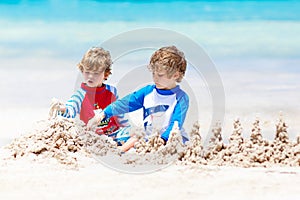 Two kid boys building sand castle on tropical beach of Boracay, Philippines