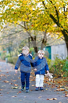 Two kid boys walking together in autumn park