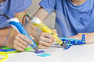 Two kid hands creating with 3d printing pens