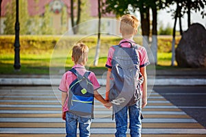Two kids with backpacks walking on the road, holding. School tim photo