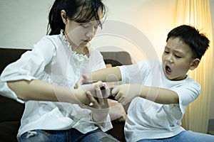 Two kids boy and child girl fighting for smartphone,sibling pulling mobile phone one another,shout and quarrel,children arguing photo