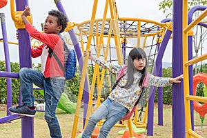 Two kids boy and girl having fun to play on children`s climbing